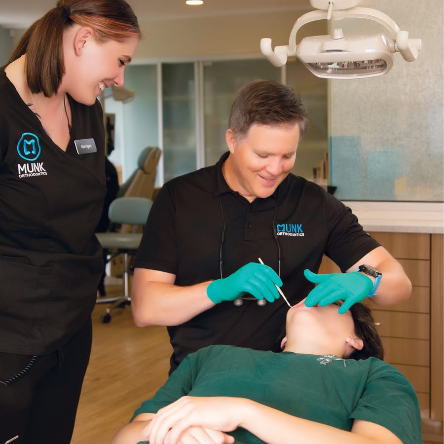 Dr. Munk and a Munk Orthodontics team member examine the mouth of a young patient.