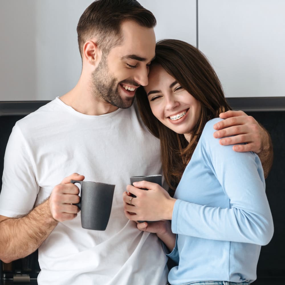 A man with braces smiles and looks down at his phone.