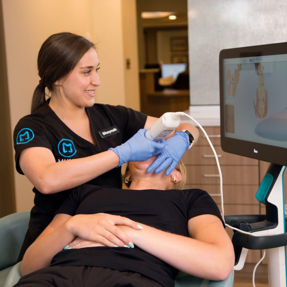 A team member of Munk Orthodontics uses a 3D scanner on a patient.